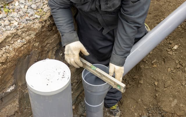 排水管に水準器を当てて施工する職人の手元